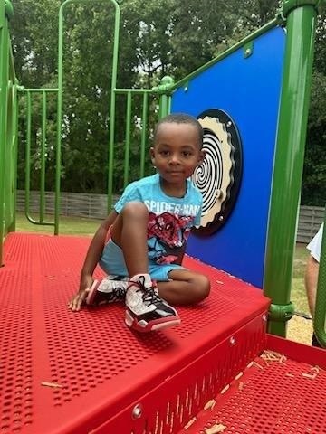 Little boy sitting on the platform of the slide posing for the camera.