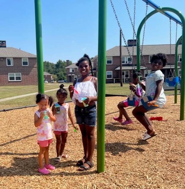A group of children on and around a swing set on the new playground.