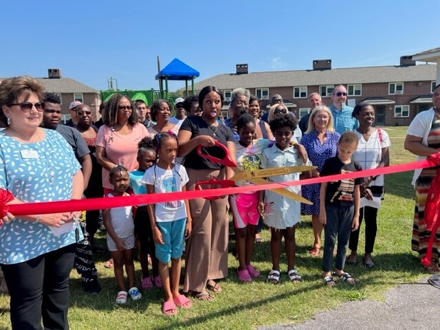 A group of people watching while the ribbon is cut to open the new playground.