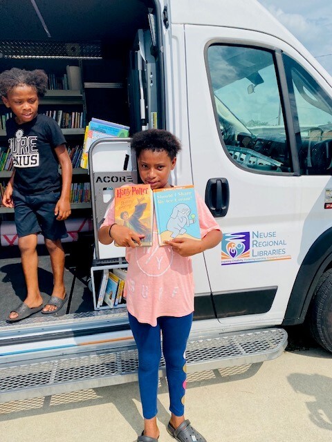 Young Lady who picked out books from the Digital Resource Rover van while a little boy stands in the van.
