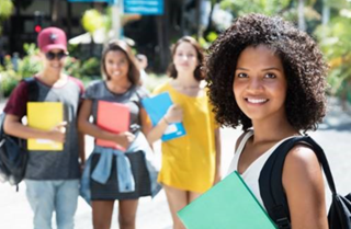 Student holding a binder with her classmates behind her.