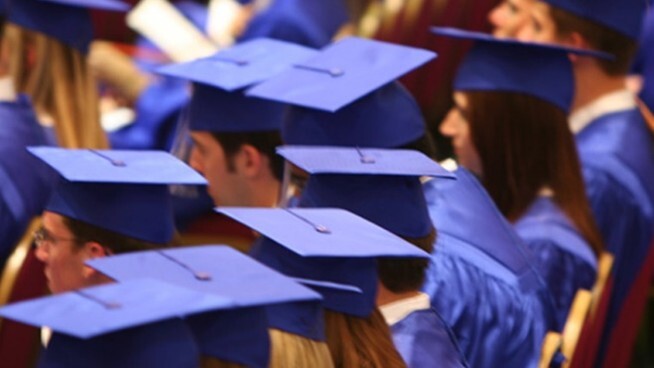 Graduates in cap and gown sitting in rows. 