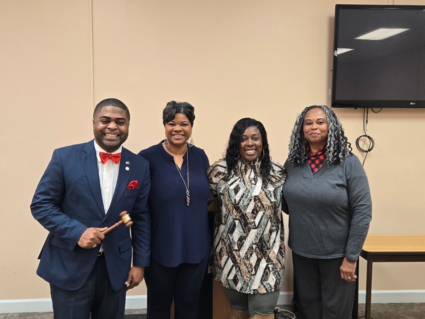 A group of four people standing and smiling for a picture.