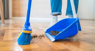 A person sweeping dirt into a dustpan.