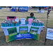  A woman sits at the Kinston Housing table, that has cups filled with goodies. 
