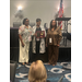  Three women smile for a picture holding an award 